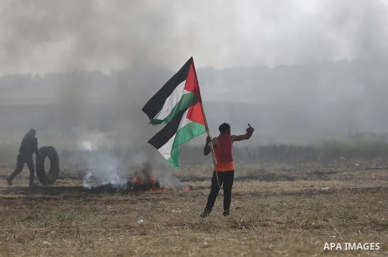 Palestinian protesters react to a tear gas fired by Israeli security forces during clashes in a tent city protest at Israel-Gaza border, in the southern Gaza Strip April 5, 2018. Photo by Ashraf Amra