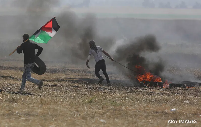 Palestinian protesters react to a tear gas fired by Israeli security forces during clashes in a tent city protest at Israel-Gaza border, in the southern Gaza Strip April 5, 2018. Photo by Ashraf Amra