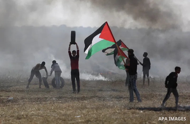 Palestinian protesters react to a tear gas fired by Israeli security forces during clashes in a tent city protest at Israel-Gaza border, in the southern Gaza Strip April 5, 2018. Photo by Ashraf Amra
