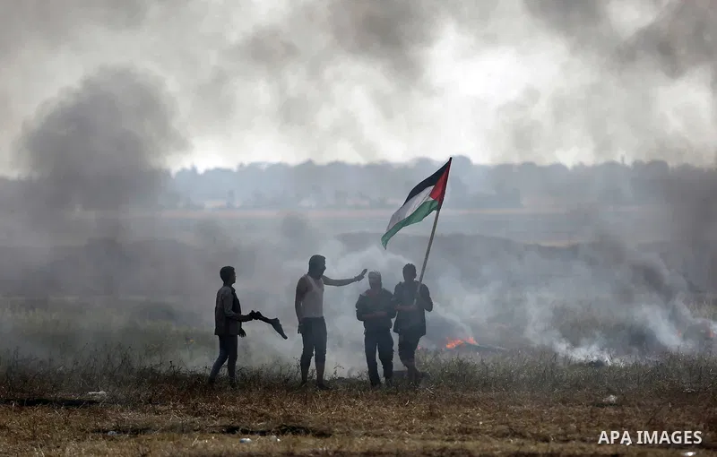 Palestinian protesters react to a tear gas fired by Israeli security forces during clashes in a tent city protest at Israel-Gaza border, in the southern Gaza Strip April 5, 2018. Photo by Ashraf Amra