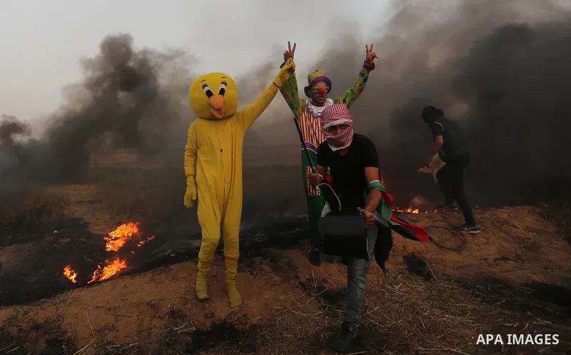 Palestinians wearing costumes are seen at the clashes scene at Israel-Gaza border in the southern Gaza Strip April 5, 2018. Photo by Ashraf Amra