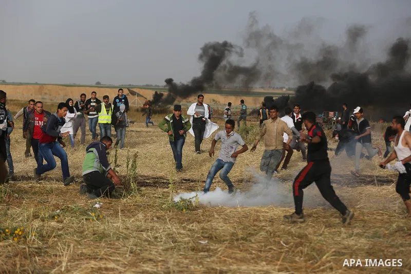 Palestinian protesters react to a tear gas fired by Israeli security forces during clashes in a tent city protest at Israel-Gaza border, in the southern Gaza Strip April 5, 2018. Photo by Ashraf Amra