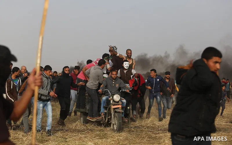Palestinian protesters react to a tear gas fired by Israeli security forces during clashes in a tent city protest at Israel-Gaza border, in the southern Gaza Strip April 5, 2018. Photo by Ashraf Amra