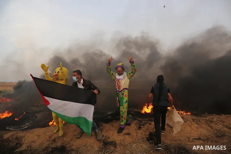 Palestinians wearing costumes are seen at the clashes scene at Israel-Gaza border in the southern Gaza Strip April 5, 2018. Photo by Ashraf Amra