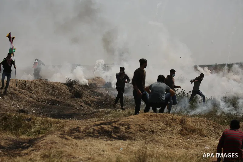 Palestinians run for cover from tear gas canisters fired by Israeli security forces during clashes at the Israel-Gaza border in a tent city protest demanding the right to return to their homeland, in east of Gaza city on...