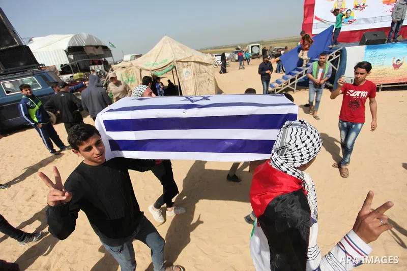 Palestinians children hold a coffin covered with Israeli flag during a tent city protest along the Israel border with Gaza, demanding the right to return to their homeland, in Jabalia in the northern of Gaza strip on Apr...