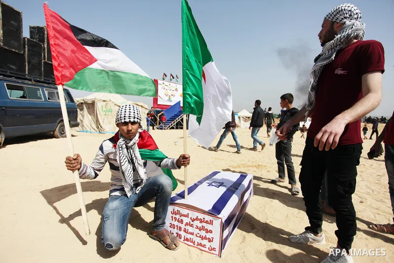 Palestinians children hold a coffin covered with Israeli flag during a tent city protest along the Israel border with Gaza, demanding the right to return to their homeland, in Jabalia in the northern of Gaza strip on Apr...
