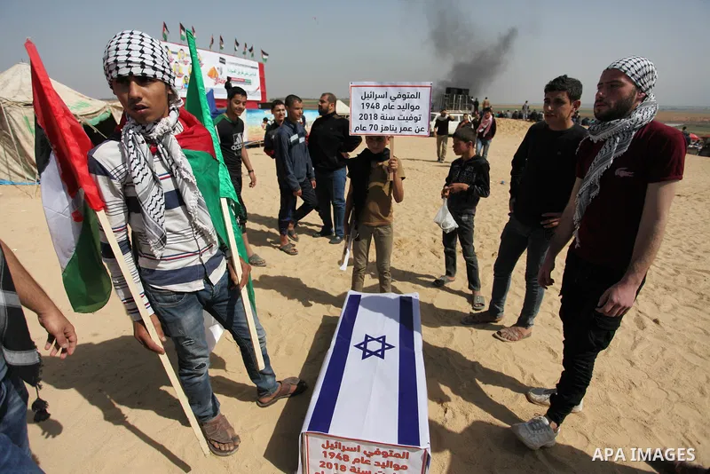 Palestinians children hold a coffin covered with Israeli flag during a tent city protest along the Israel border with Gaza, demanding the right to return to their homeland, in Jabalia in the northern of Gaza strip on Apr...