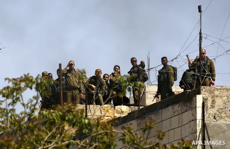 Israeli security forces stand guard on a house roof during clashes with Palestinian protesters following a demonstration, in the West Bank city of Hebron, on April 6, 2018. Photo by Wisam Hashlamoun