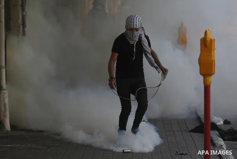 A Palestinian protester throws a stone towards Israeli soldiers during clashes following a demonstration, in the West Bank city of Hebron, on April 6, 2018. Photo by Wisam Hashlamoun
