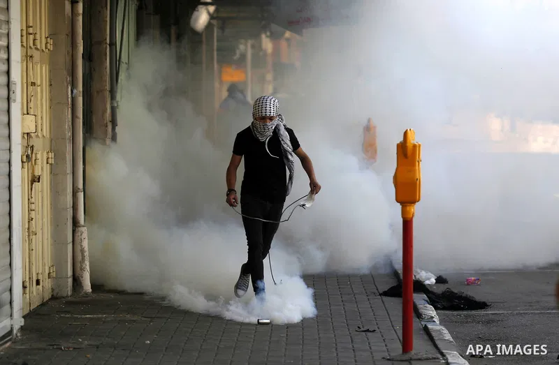 A Palestinian protester throws a stone towards Israeli soldiers during clashes following a demonstration, in the West Bank city of Hebron, on April 6, 2018. Photo by Wisam Hashlamoun