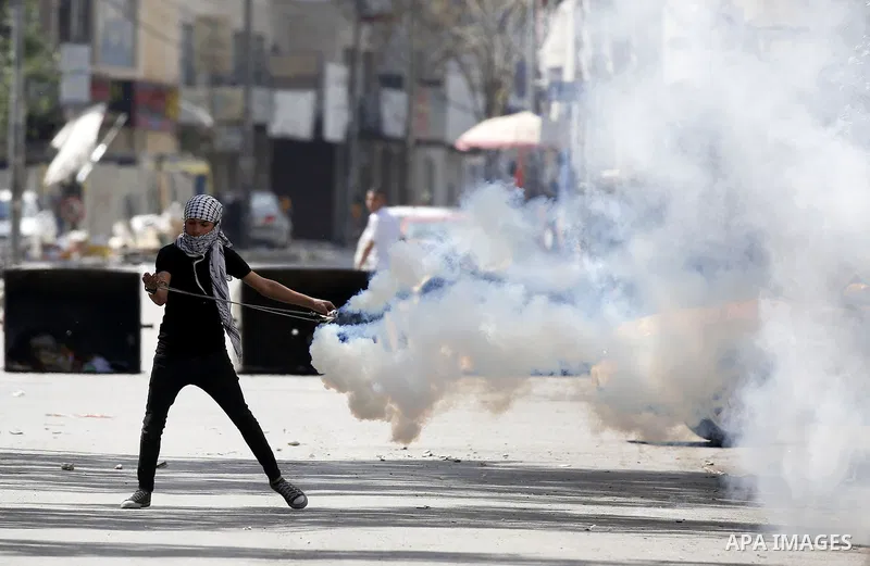 A Palestinian protester throws a stone towards Israeli soldiers during clashes following a demonstration, in the West Bank city of Hebron, on April 6, 2018. Photo by Wisam Hashlamoun