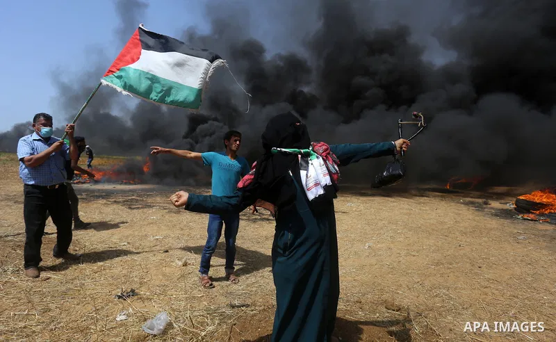 A Palestinian woman uses a slingshot to hurl stones towards Israeli security forces during clashes at the Israel-Gaza border in a tent city protest demanding the right to return to their homeland, in Khan Younis in the s...