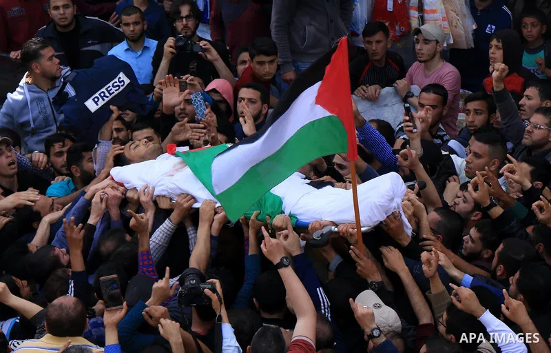 Mourners and journalists carry the body of Palestinian journalist Yasser Murtaja, 30, who died from his injuries after he was shot by Israeli security forces during clashes at the Israel-Gaza border on Friday, during his...