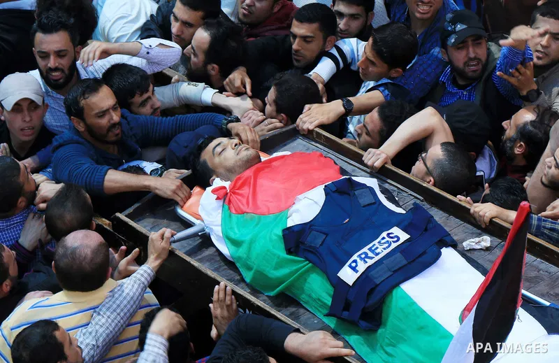 Mourners and journalists carry the body of Palestinian journalist Yasser Murtaja, 30, who died from his injuries after he was shot by Israeli security forces during clashes at the Israel-Gaza border on Friday, during his...