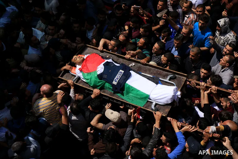 Mourners and journalists carry the body of Palestinian journalist Yasser Murtaja, 30, who died from his injuries after he was shot by Israeli security forces during clashes at the Israel-Gaza border on Friday, during his...