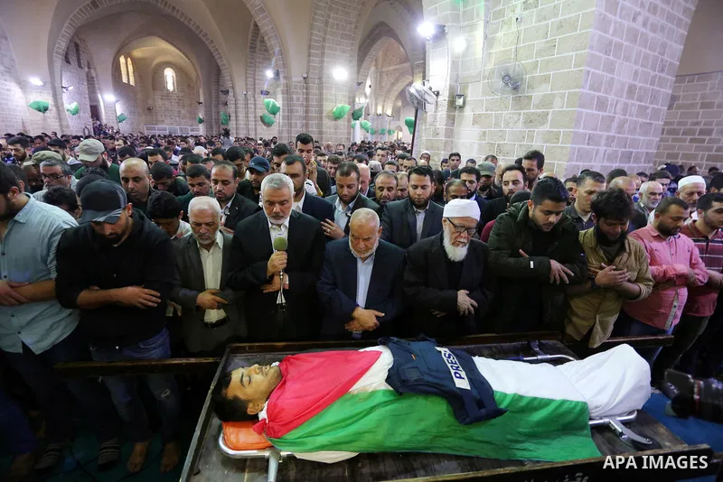 Hamas Chief Ismail Haniyeh pray over the body of Palestinian journalist Yasser Murtaja, 30, who died from his injuries after he was shot by Israeli security forces during clashes at the Israel-Gaza border on Friday, duri...