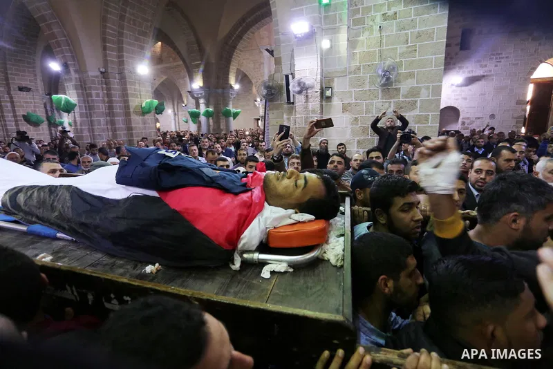 Mourners and journalists carry the body of Palestinian journalist Yasser Murtaja, 30, who died from his injuries after he was shot by Israeli security forces during clashes at the Israel-Gaza border on Friday, during his...