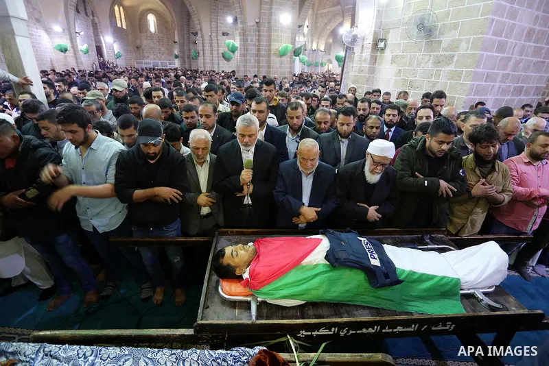Hamas Chief Ismail Haniyeh pray over the body of Palestinian journalist Yasser Murtaja, 30, who died from his injuries after he was shot by Israeli security forces during clashes at the Israel-Gaza border on Friday, duri...