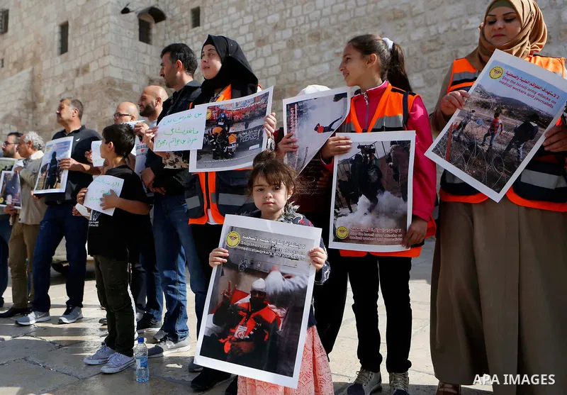 Palestinian medicals hold placards during a protest demanding to stop Israeli attacks on paramedics and journalists outside Church of the Nativity in the West Bank city of Bethlehem, on April 8, 2018. Photo by Wisam Hash...