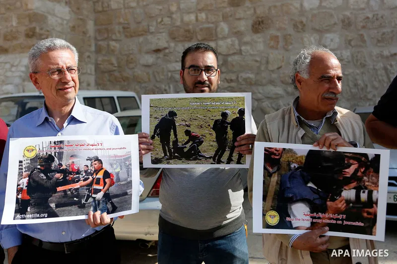 Palestinian medicals hold placards during a protest demanding to stop Israeli attacks on paramedics and journalists outside Church of the Nativity in the West Bank city of Bethlehem, on April 8, 2018. Photo by Wisam Hash...