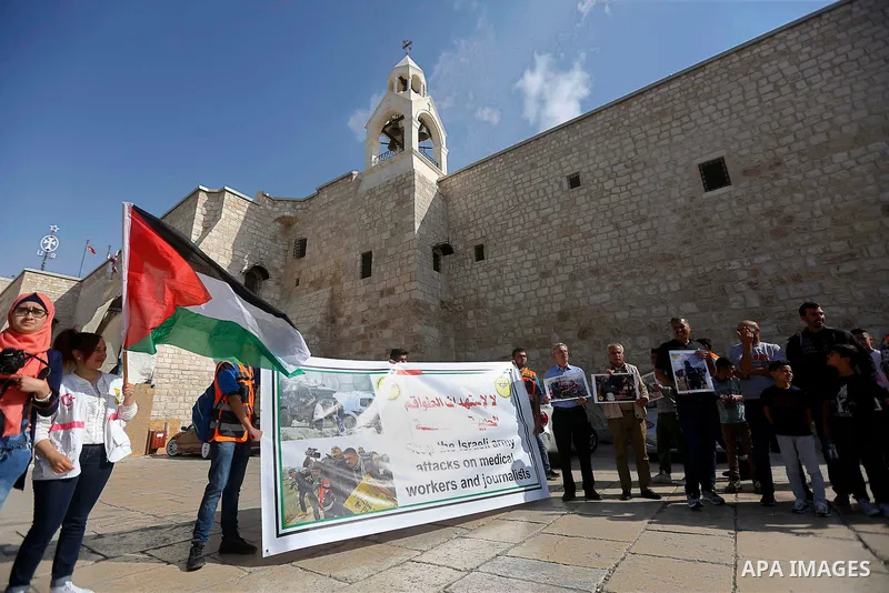 Palestinian medicals hold placards during a protest demanding to stop Israeli attacks on paramedics and journalists outside Church of the Nativity in the West Bank city of Bethlehem, on April 8, 2018. Photo by Wisam Hash...