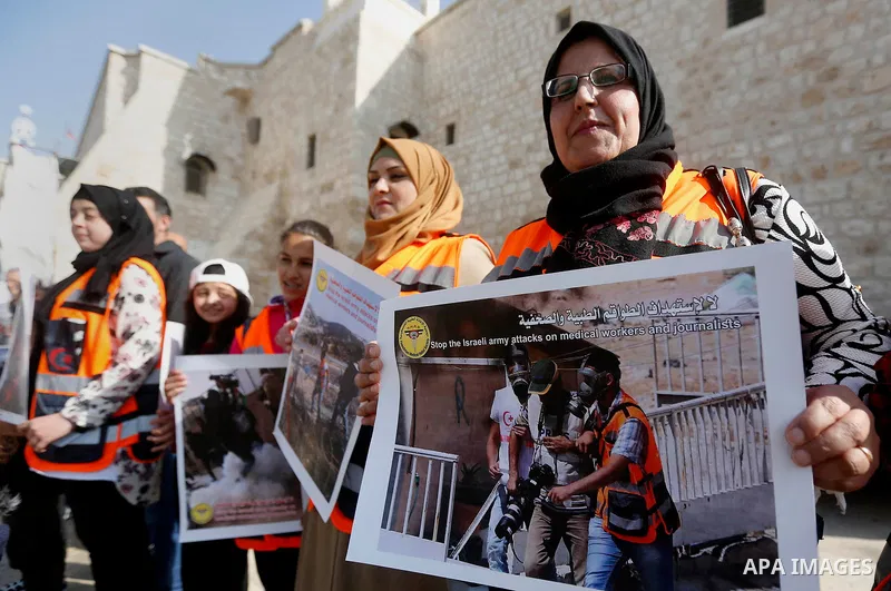 Palestinian medicals hold placards during a protest demanding to stop Israeli attacks on paramedics and journalists outside Church of the Nativity in the West Bank city of Bethlehem, on April 8, 2018. Photo by Wisam Hash...