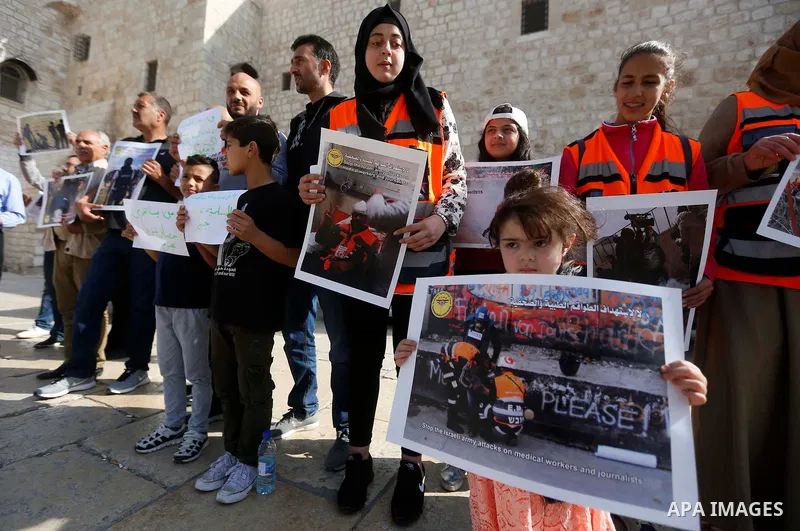 Palestinian medicals hold placards during a protest demanding to stop Israeli attacks on paramedics and journalists outside Church of the Nativity in the West Bank city of Bethlehem, on April 8, 2018. Photo by Wisam Hash...