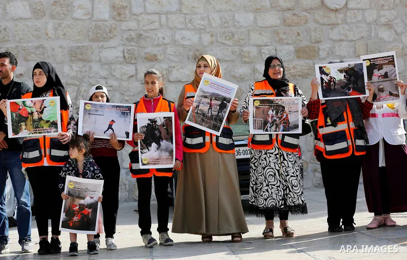 Palestinian medicals hold placards during a protest demanding to stop Israeli attacks on paramedics and journalists outside Church of the Nativity in the West Bank city of Bethlehem, on April 8, 2018. Photo by Wisam Hash...