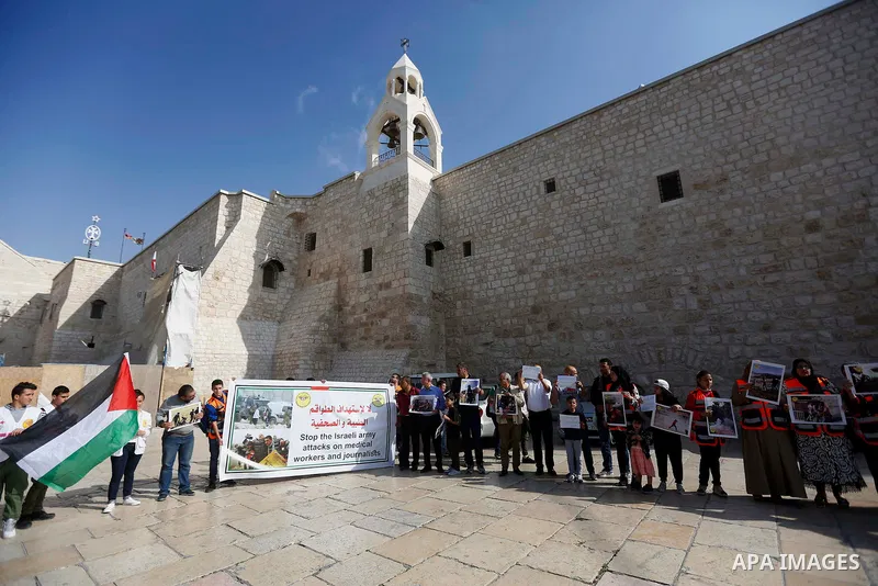 Palestinian medicals hold placards during a protest demanding to stop Israeli attacks on paramedics and journalists outside Church of the Nativity in the West Bank city of Bethlehem, on April 8, 2018. Photo by Wisam Hash...