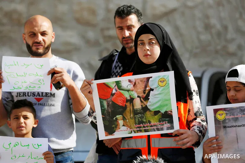 Palestinian medicals hold placards during a protest demanding to stop Israeli attacks on paramedics and journalists outside Church of the Nativity in the West Bank city of Bethlehem, on April 8, 2018. Photo by Wisam Hash...