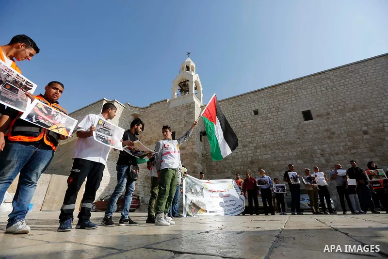 Palestinian medicals hold placards during a protest demanding to stop Israeli attacks on paramedics and journalists outside Church of the Nativity in the West Bank city of Bethlehem, on April 8, 2018. Photo by Wisam Hash...