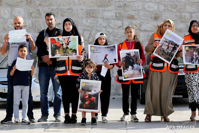 Palestinian medicals hold placards during a protest demanding to stop Israeli attacks on paramedics and journalists outside Church of the Nativity in the West Bank city of Bethlehem, on April 8, 2018. Photo by Wisam Hash...