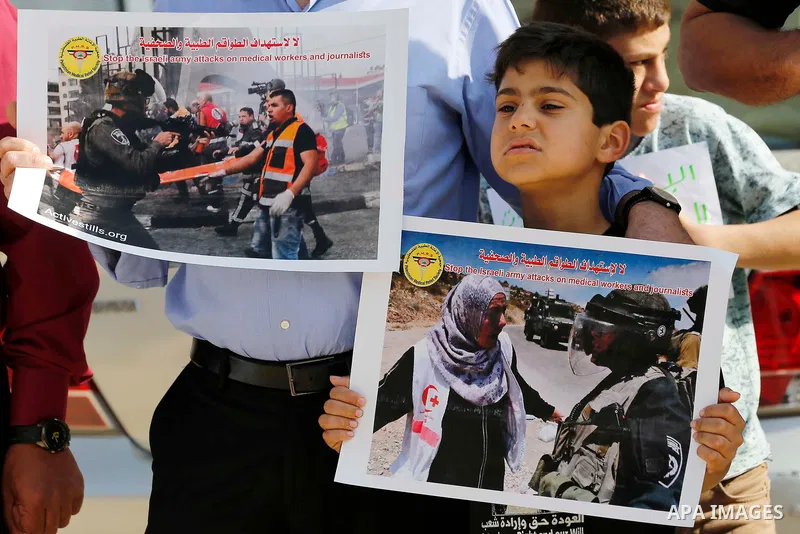 Palestinian medicals hold placards during a protest demanding to stop Israeli attacks on paramedics and journalists outside Church of the Nativity in the West Bank city of Bethlehem, on April 8, 2018. Photo by Wisam Hash...