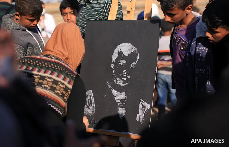 A Palestinian female painter puts the finishing touch to a poster of Palestinian journalist Yasser Murtaja, as fellow journalists take part in a protest against his killing at the Israel-Gaza border, in Khan Younis in th...