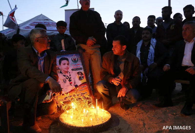 Palestinians light candles during a symbolic birthday party for Palestinian Teenager Hussein Madi, who was killed during clashes with Israeli security forces at the Israel-Gaza border, on his 14th birthday in the east of...