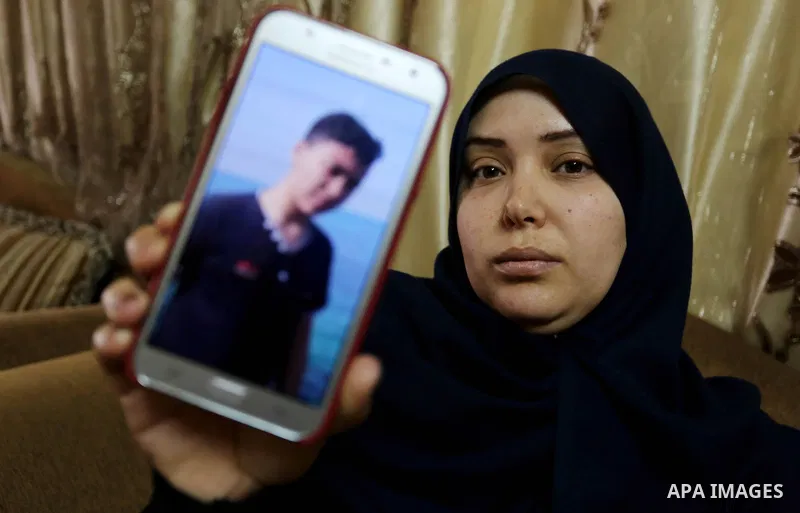 The mother of Palestinian Teenager Hussein Madi, who was killed during clashes with Israeli security forces, holds a mobile phone and showing the picture of her son at her house in Gaza city on April 9, 2018. Photo by As...