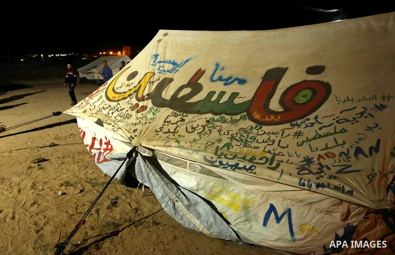 Palestinians sit next to tents during a tent city protest east of Gaza City April 9, 2018. Photo by Ashraf Amra