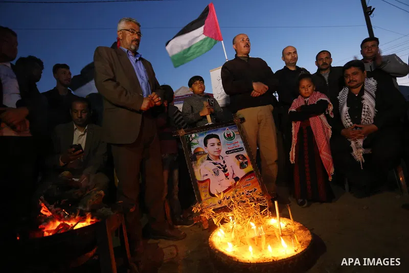 Palestinians light candles during a symbolic birthday party for Palestinian Teenager Hussein Madi, who was killed during clashes with Israeli security forces at the Israel-Gaza border, on his 14th birthday in the east of...