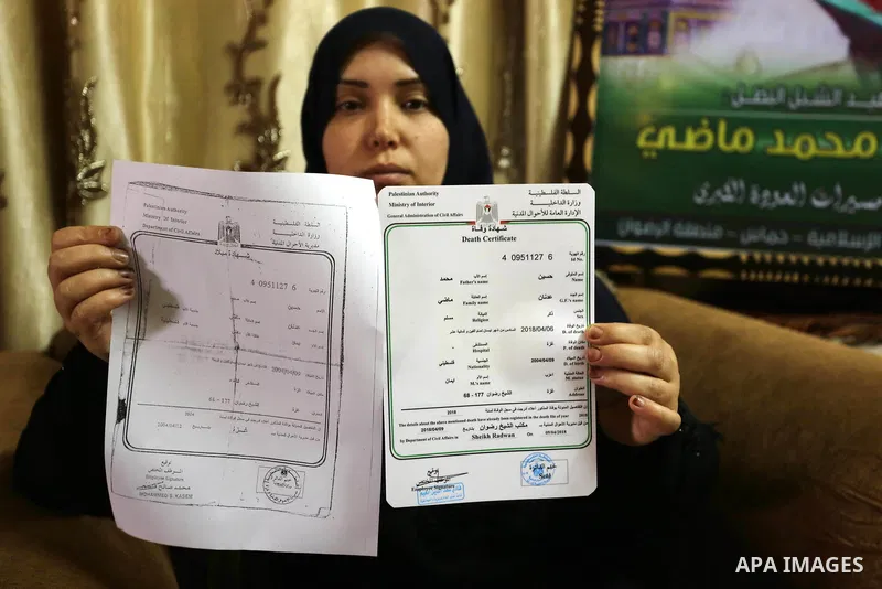 The mother of Palestinian Teenager Hussein Madi, who was killed during clashes with Israeli security forces, holds his birth and death certificates at her house in Gaza city on April 9, 2018. Photo by Ashraf Amra
