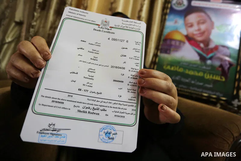 The mother of Palestinian Teenager Hussein Madi, who was killed during clashes with Israeli security forces, holds his death certificate at her house in Gaza city on April 9, 2018. Photo by Ashraf Amra