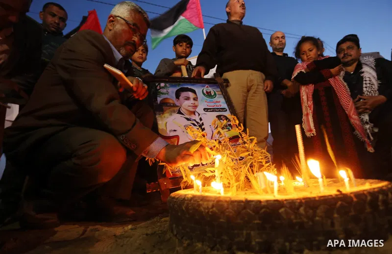 Palestinians light candles during a symbolic birthday party for Palestinian Teenager Hussein Madi, who was killed during clashes with Israeli security forces at the Israel-Gaza border, on his 14th birthday in the east of...