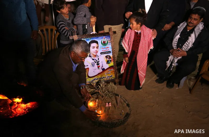 Palestinians light candles during a symbolic birthday party for Palestinian Teenager Hussein Madi, who was killed during clashes with Israeli security forces at the Israel-Gaza border, on his 14th birthday in the east of...