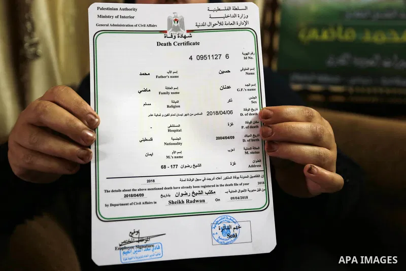 The mother of Palestinian Teenager Hussein Madi, who was killed during clashes with Israeli security forces, holds his death certificate at her house in Gaza city on April 9, 2018. Photo by Ashraf Amra