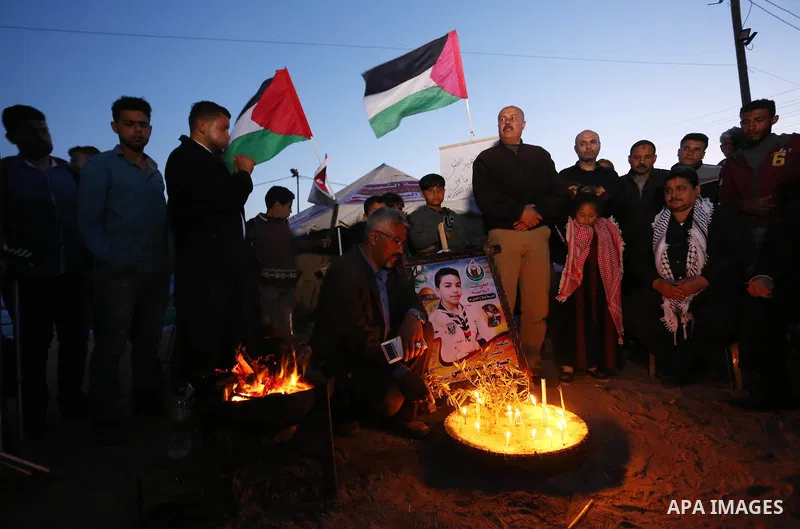 Palestinians light candles during a symbolic birthday party for Palestinian Teenager Hussein Madi, who was killed during clashes with Israeli security forces at the Israel-Gaza border, on his 14th birthday in the east of...