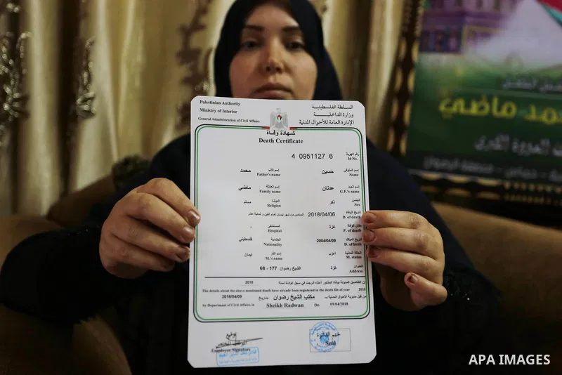 The mother of Palestinian Teenager Hussein Madi, who was killed during clashes with Israeli security forces, holds his death certificate at her house in Gaza city on April 9, 2018. Photo by Ashraf Amra