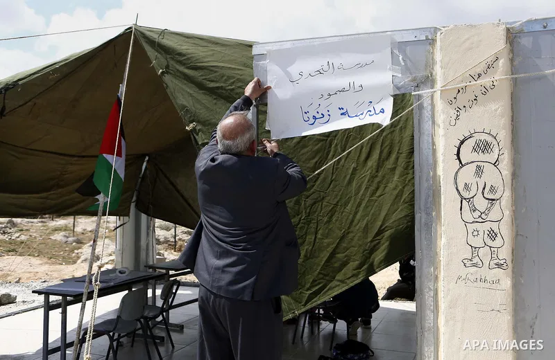 Palestinians gather at the site of their school after Israeli forces it was demolished by Israeli security forces who claim it was built on illegal land, in the West Bank city of Hebron on April 10, 2018. Photo by Wisam...