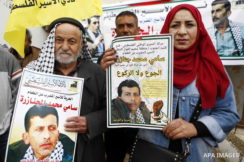 Palestinians hold posters depicting Sami al-Janazra who is in hunger strike at Israeli jails, during a protest to show solidarity with al-Janazra in the West Bank city of Hebron on April 10, 2018. Photo by Wisam Hashlamo...