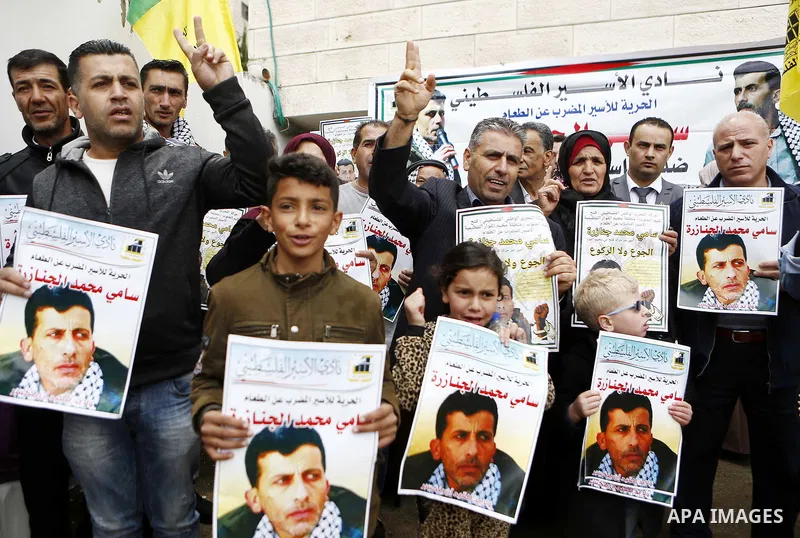Palestinians hold posters depicting Sami al-Janazra who is in hunger strike at Israeli jails, during a protest to show solidarity with al-Janazra in the West Bank city of Hebron on April 10, 2018. Photo by Wisam Hashlamo...