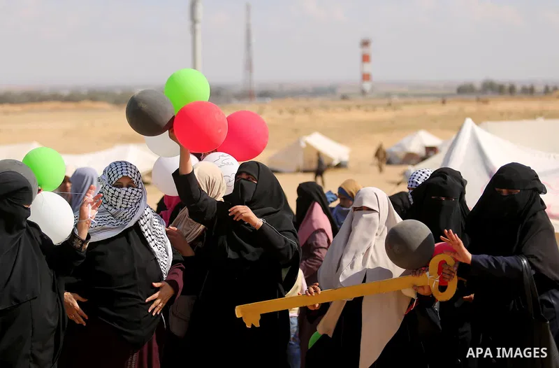 Palestinian women hold balloons during a protest demanding the right to return to their homeland, at the Israel-Gaza border, in Rafah in the southern Gaza Strip on April 10, 2018. Photo by Ashraf Amra
